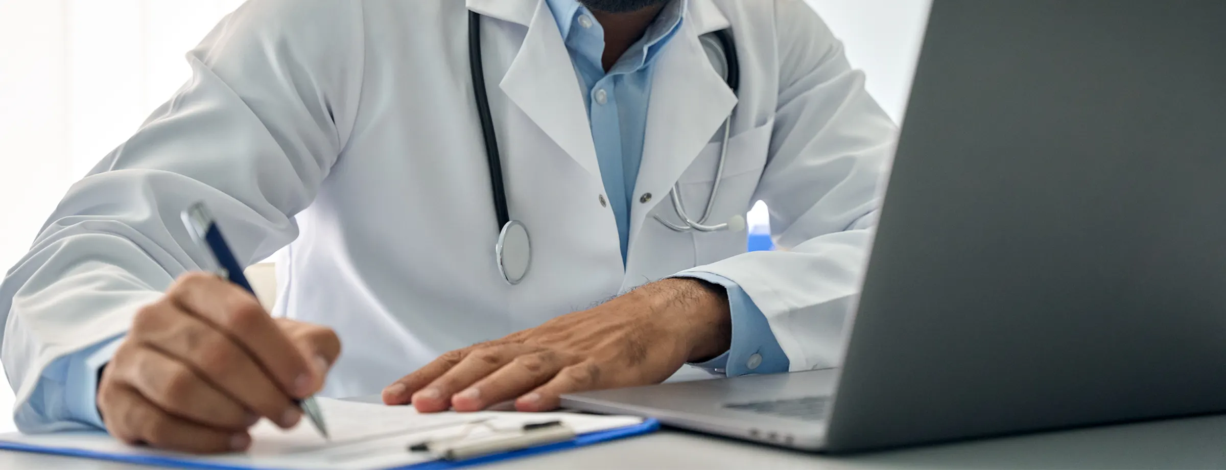Médico do trabalho registrando informações de saúde ocupacional no computador